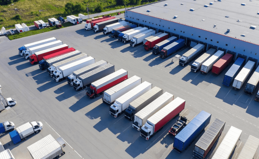 A parking lot with many semi trucks standing by