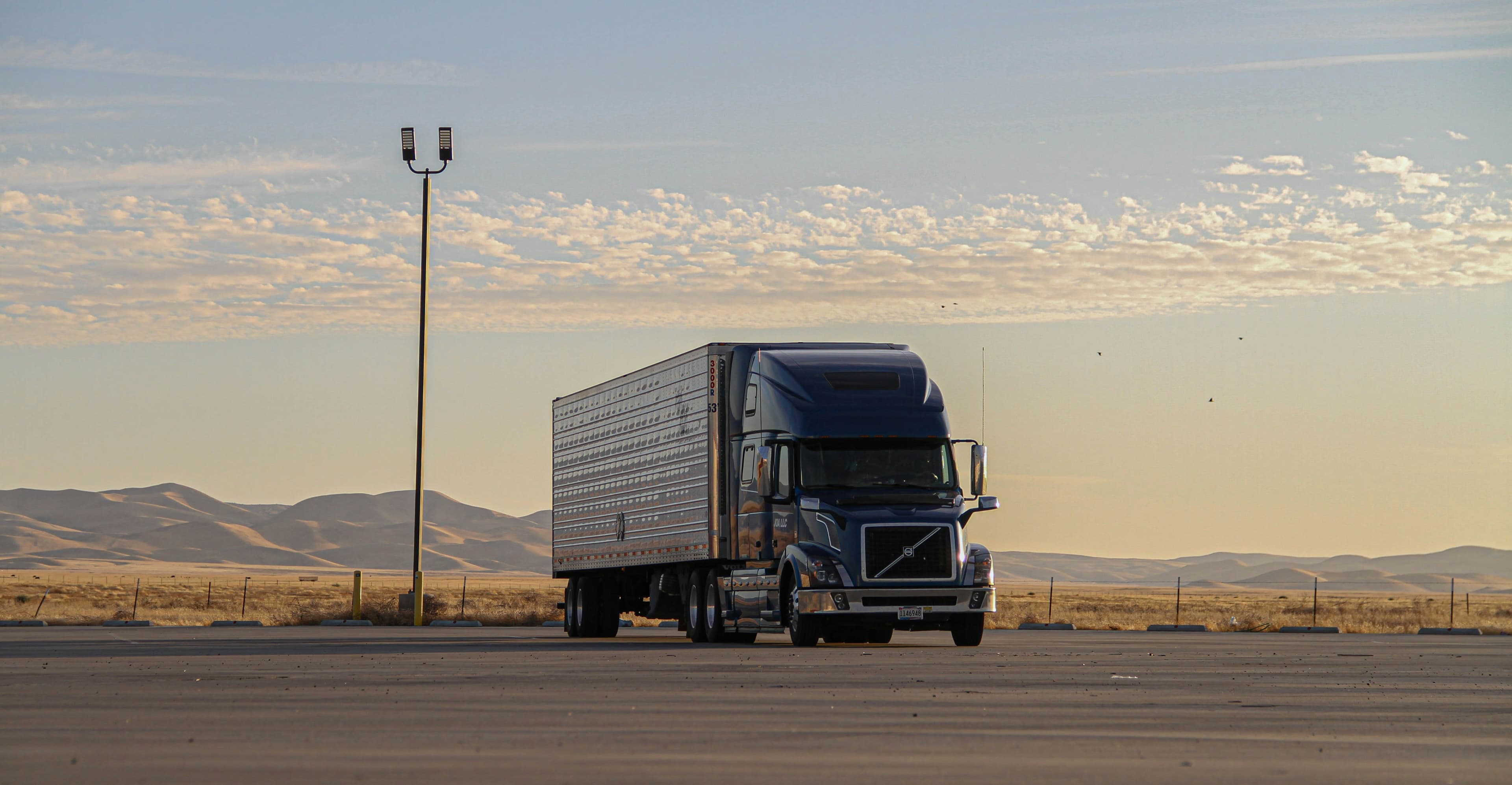 A black freight truck driving on a road during the day